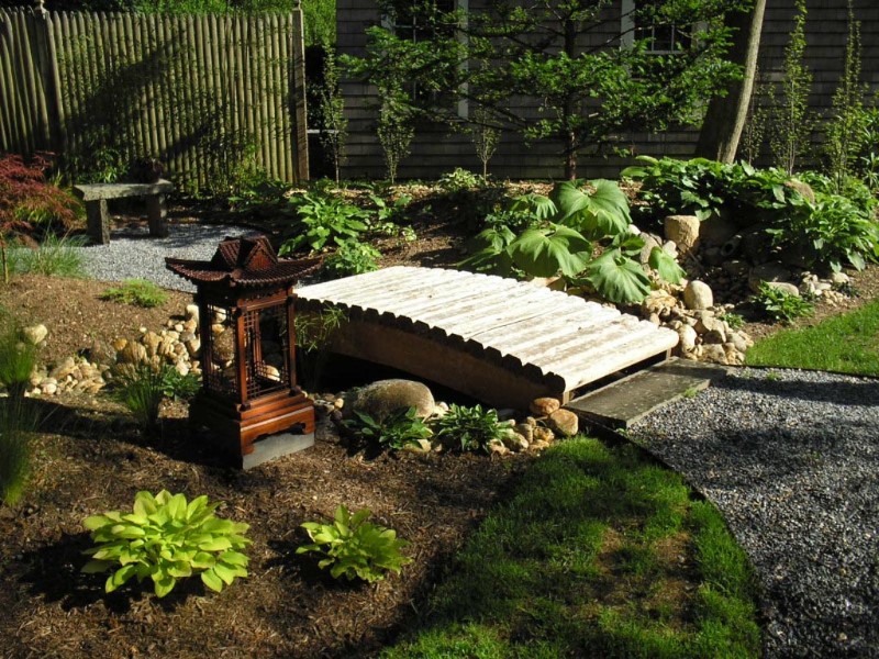 japanese garden bridge in a simple outdoor design with a wooden lantern