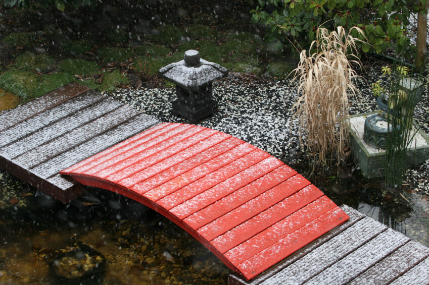 small red footbridge during winter in a japanese garden