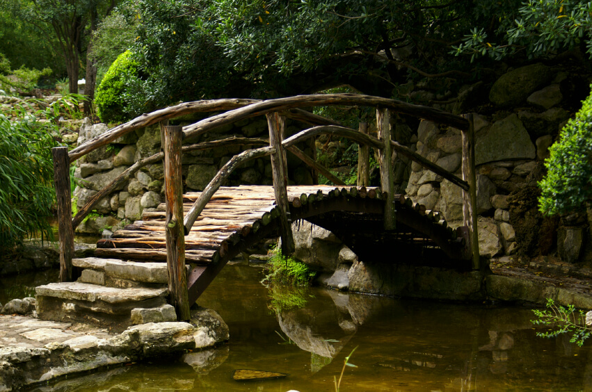 vintage wooden footbridge using recycle trunk in a classical japanese garden
