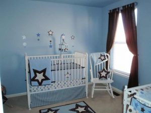 baby crib in a blue room for baby boy with rocking chair besides