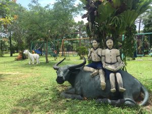 two khmer children on a buffalo statue in an organic farm